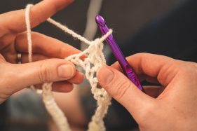 person-holding-purple-crochet-hook-and-white-yarn-3945638